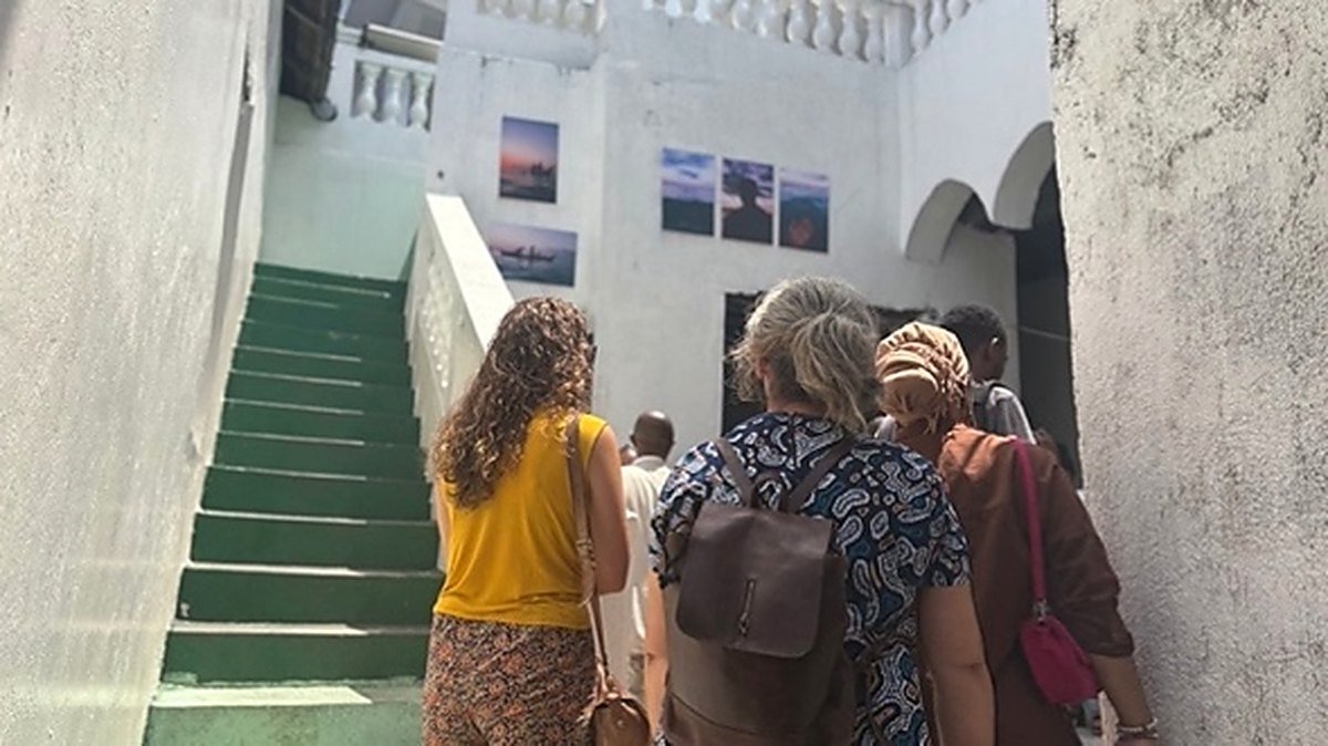 Visiteurs montant un escalier de la médina de Moroni où sont accrochées des photographies.